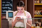 Maja (Godiva Adela) lässt sich bei der Arbeit von ihrem Handy ablenken.