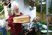 Gary Muehlberger tossing a log to the side of his wood pile and taking inventory before winter hits the community.