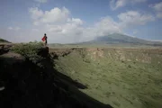 Tanzania: Hazen standing on the edge of a caldera or crater created by an old volcano.
