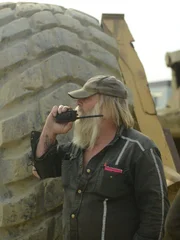 Tony Beets radoing, stood in front of excavator.