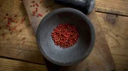 Mortar with dried red peppercorns on wood, elevated view