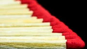 Side view of a row of wooden matches aligned on a black background