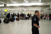 Jamaica, New York, USA: Customs and Border Protection officer Joe Finn takes a call while travelers wait in line at John F. Kennedy International Airport.