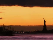 The Statue of Liberty at a distance at sunset.