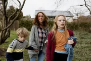 Dea (Christine Albeck Børge, Mi.) ergreift mit Theo (Noah Storm Otto, li.) und Holly (Flora Ofelia Hofmann Lindahl, re.) die Flucht.