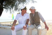 Kapitän Burger (Sascha Hehn) und Peter Hellmann (Volkert Kraeft) sitzen auf einem alten Kahn am Strand und unterhalten sich.