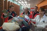Notarzt Haase (Fabian Harloff, l.) und seine Rettungssanitäter (Komparsen) liefern die verunglückte Jette Kruse (Carmen-Maja Antoni, liegend) bei Jasmin (Gerit Kling, r.) im EKH ab.