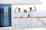 Dr. Sander (Nick Wilder), Beatrice (Heide Keller) und Kapitän Burger (Sascha Hehn) stehen winkend an Deck der MS Amadea.