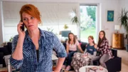 Rebecca Schenk (Henny Reents, l.) erhält einen dringenden Anruf, während ihre Töchter Kim Schenk (Lola Brauser, 2.v.l.), Antonia Schenk (Sina Fredrich, 2.v.r.) und Sofie Schenk (Emilie Neumeister, r.) besorgt von der Couch aus zuhören.