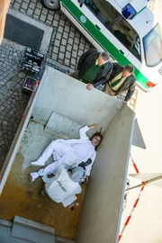 Der Reproduktionsmediziner Dr. Hecht liegt tot in einem Schuttcontainer vor seiner Praxisklinik. Pathologin Dr. Caroline Fuchs (Susu Padotzke), der tote Dr. Hecht (Komparse), Girwidz (Michael Brandner, oben, l.), Hubert (Christian Tramitz, oben, r.)