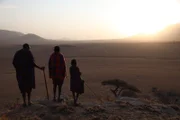 Massai-Viehhirte Parakapooni, sein Bruder und sein Sohn blicken über die braunen Ebenen der Serengeti in Tansania.