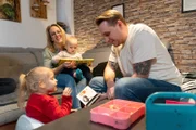 Wie geht es Menschen nach der Gentherapie? Familie Verton im Wohnzimmer beim Bücherlesen. Von links: Emilia, Stephie mit Lio und Fabian