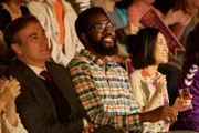 Schulleiter Bernard Ashford (Derek Riddell, l.), der Stipendiaten-Betreuer Gus (Daniel Lawrence Taylor, M.) und Japanischlehrerin Mrs. Kaneko (Yuriri Naka, r.) schauen sich gemeinsam den Roboter-Wettkampf an.