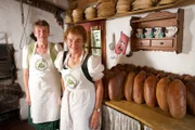 Die beiden Fuschler Bäuerinnen Justine Stöllinger und Maria Klaushofer posieren für ein Foto in der Rumingmühle beim Holzofenbrot backen während ServusTVs „Heimatleuchten – Meer Gefühl - Im Salzburger Land“ in Fuschl am See, Salzburg, Österreich.
