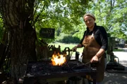 Schmiedin und Biobäuerin Monika Kaiser posiert für ein Foto beim Schmieden in ihrer Natur Schmiede Eisenkraut während ServusTVs „Heimatleuchten – Meer Gefühl - Im Salzburger Land“ in Seeham, Trumer Seenland, Oberösterreich, Österreich.