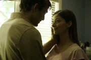 A woman looks at a man while he caresses her face.
