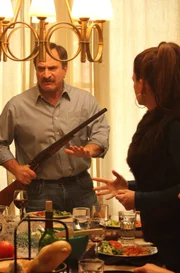 Alfred Ross holding a shot gun at the dinner table while the family fights.