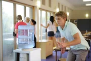 Im Klassenraum spielt das Wasser verrückt. Will (Luke Mitchell) versucht den Wasserbehälter festzuhalten, um Rikki, Cleo und Bella vor Spritzwasser zu schützen.