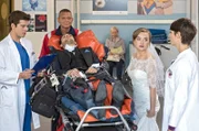 Inga Lanz (Kyra Sophia Kahre, 2.v.r.) und Michael Martin (Daniel Fritz, v.M. mit Komparsen, h.M.) kommen aufgewühlt in der Notaufnahme an: Eigentlich wollten die beiden heute heiraten, doch der angehende Bräutigam wurde angefahren – von niemand anderem als der Braut. Ben Ahlbeck (Philipp Danne, l.) und Dr. Theresa Koshka (Katharina Nesytowa, r.) kümmern sich um die beiden.