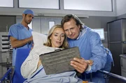 Nach der erfolgreichen Geburt zeigt Paul (Steffen Münster, rechts) seiner Frau Antje, (Birgit Würz, Mitte) Bilder von ihrem Sohn "Leo". Niklas (Roy Peter Link) ist erleichtert, dass der Eingriff geglückt ist.