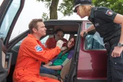 Notarzt Dr. Haase (Fabian Harloff, l.) kümmert sich um das Unfallopfer Tanja Grabow (Julia Becker, M.) und gibt Melanie (Sanna Englund, r.) einen ersten Bericht zum Unfallgeschehen.