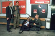 Arthur Rix (Herbert Fritsch, r.) verdeutlicht Dr. Robert Kolmaar (Ulrich Mühe, l.), Kommissar Hoffer (Jörg Gudzuhn, 2.v.l.) und Wim Geddes (Walter Kreye, 2.v.r.) vom Staatsschutz, dass man nach seinen Regeln zu spielen hat.