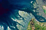 Beim Blick aus einer Höhe von mehreren Hundert Kilometern erscheinen Landschaften als ein Kunstwerk aus Farben, Formen und Mustern: die Elbmündung vom Satelliten aus.