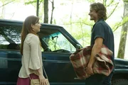 A young man and woman stand next to a car.