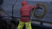 A deckhand on the Northwestern throws lines overboard.