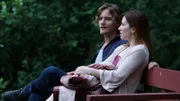A young woman and man sit on a bench.