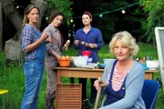 ARD DIE DIENSTAGSFRAUEN - ZWISCHEN KRAUT UND RÜBEN, Die Freundinnen Eva (Saskia Vester, vorne), Kiki (Mimi Fiedler, 2. v. re.) und Judith (Clelia Sarto, 2. v. li.) beobachten amüsiert das Treiben von Estelle und Steiner. Einzig Caroline (Janna Striebeck, li.) ist etwas misstrauisch.