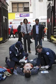 Reid (Matthew Gray Gubler, stehend l.) und David Rossi (Joe Mantegna, stehend r.) können nicht glauben, dass Detective Cooper (Erik Palladino, liegend) von den Tätern getroffen wurde ...
