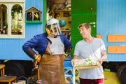Fritz (Guido Hammesfahr, r.) versucht seinen Nachbarn David (Daniel Zillmann) mit einem leckeren Kräuterkuchen davon zu überzeugen, seinen verrückten Kampf gegen Wildkräuter aufzugeben.