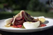 Bei Henri in Frankreich gibt es Ofentomaten mit Pimentos, Ei, Zwiebeln, Knoblauch und gegrilltem Schinken.