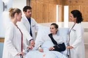 Julia Berger (Mirka Pigulla, l.), Dr. Niklas Ahrend (Roy Peter Link, 2.v.l.) und Dr. Leyla Sherbaz (Sanam Afrashteh, r.) besuchen Zoe (Melina Fabian, M.) nach der OP.