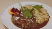 Das Hauptgericht der Gaststätte  "Der Obere Wirt zum Queri" in Frieding/Andechs wird auf einem weißem Teller präsentiert -  Rindsbraten vom Angus-Weideochsen mit sämiger Burgundersoße, Serviettenknödl, dazu gerührte Preiselbeeren.