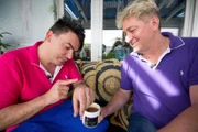 Jede Woche finden die Allestester eine neue, aufregende Lieferung eingepackt vor ihrer Haustüre, um sie auf Herz und Nieren zu testen. Unser Foto zeigt das Pärchen Matthias (32, l.) und Hubert (47) mit dem Testobjekt "Enthaarungs-Zuckerpaste".