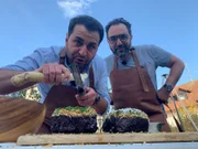 Ali Güngörmüş (vorne) reibt Kren über das Fleisch, während Adnan Maral zuschaut.
