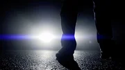 Eine Person steht in der Dunkelheit