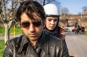 Bijan (Omid Memar) und Betty (Ella Lee) fahren mit dem Motorrad und werden von Schneider (Raphael Westermeier) und seinen Kollegen angehalten und &uuml;berpr&uuml;ft.