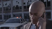 Demery is on his cell in front of a rundown building.