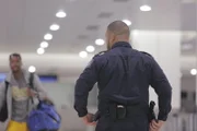 A CBP Officer observes passengers arriving on international flights at Miami International Airport.