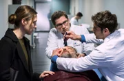 Gero (Nicki von Tempelhoff, v.M.) hat kurz nach der Einlieferung ins JTK das Bewusstsein verloren. Elias Bähr (Stefan Ruppe, h.M.) und Dr. Niklas Ahrend (Roy Peter Link, r.) entscheiden, er muss sofort in den OP. Geros Frau Christine (Nike Fuhrmann, l.) bangt um das Leben ihres Mannes.