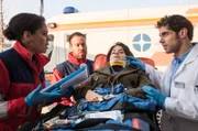 Vivi (Jane Chirwa, l.) kommt mit dem Rettungswagen am JTK an. Sie vermutet eine Schädefraktur bei Tina Fresen (Vanessa Jung, 2.v.r.). Dr. Niklas Ahrend (Roy Peter Link, r.) klinkt sich ein (mit Komparse, 2.v.l.).