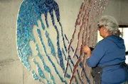 Mosaikkünstlerin Tanja Lebski beim Entgraten der scharfen Mosaiksteinchen ihres Quallenmotivs für ein Hallenbad.