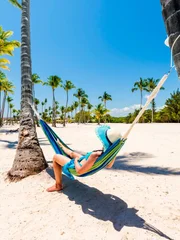Juanillo Beach (playa Juanillo), Punta Cana, Dominican Republic. Woman relaxing on a hammock on a palm-fringed beach.