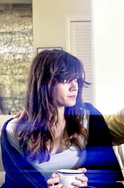Reenactment: Renee sits on the couch with her mother with her father in the background.