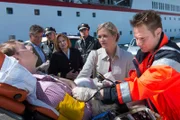 Jens Piecek (Steffen Will, l.) ist von Deck gestürzt als er die Nerven verlor und Schiffsarzt Wolf Sander (Nick Wilder, 2.v.l.) schlug. Chefhostess Beatrice (Heide Keller, M.) versteht Herrn Piecek und seine Frau Imke (Judith Hoersch, 2.v.r.), deren Geld für die Kreuzfahrtbuchung offensichtlich nicht dort angekommen ist, wo es hin sollte. Dr. Haase (Fabian Harloff, r.) verarztet den unglücklichen Passagier. Melanie (Sanna Englund, 3.v.l.) und Mattes (Matthias Schloo, 3.v.r.) beobachten das Geschehen.