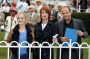 Gespannt verfolgen Nadja Bock (Floriane Daniel, M.),  Johannes Sonntag (Matthias Klimsa, r.) und Julia Klug (Friederike Kempter, l.) den Start des Hauptrennens auf der Galopprennbahn Berlin-Hoppegarten. Die Chefin hat auf den hohen Favoriten "Chardonnay" gesetzt.