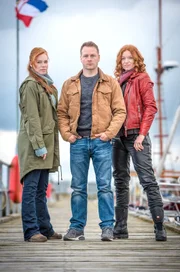 "Nord bei Nordwest - Der Transport", Der legendäre 'Nordic Ride' entlang der Ostseeküste zieht Biker aus aller Welt an. Für vier Schweden ist das Rennen aber nur ein Vorwand, um einen ganz großen Coup zu landen. Ein Transporter mit kostbaren Diamanten soll überfallen werden, während alle Aufmerksamkeit auf dem Rennspektakel ruht. Als einer der Gangster kurz vor Rennbeginn erschossen am Stand angespült wird, ist jedoch Polizistin Lona Vogts Misstrauen geweckt. Gemeinsam mit Ex-Cop Hauke Jacobs heftet sie sich an die Fersen der vermeintlich harmlosen Fremden.Im Bild (v.li.): Henny Reents (Lona Vogt), Hinnerk Schönemann (Hauke Jacobs), Marleen Lohse (Jule Christiansen).